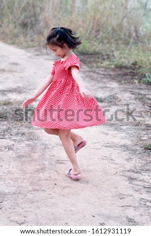 Asian child girl is spinning with fun in the field. Moving image, 