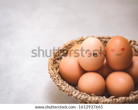 Egg lovers have happy faces of men and women on the pile of eggs in the basket with copy space. Organic egg food ingredients, Couples, Easter, Valentine's day concept.
