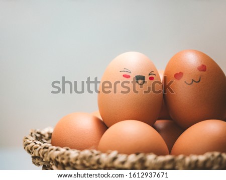 Egg lovers have happy faces of men and women on the pile of eggs in the basket with copy space. Organic egg food ingredients, Couples, Easter, Valentine's day concept.
