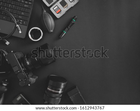 top view of work space photographer with digital camera, flash, cleaning kit, memory card, tripod and camera accessory on black table background