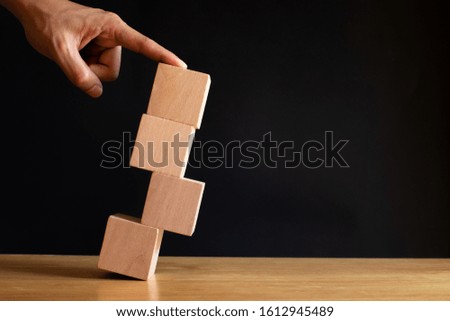 Finger pushing wooden cube on black background. Investement Risk management concept