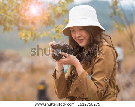 Beautiful Asian female traveller looking at the picture in the camera with blurry background.