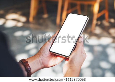 Mockup image of hands holding black mobile phone with blank desktop screen  Royalty-Free Stock Photo #1612970068