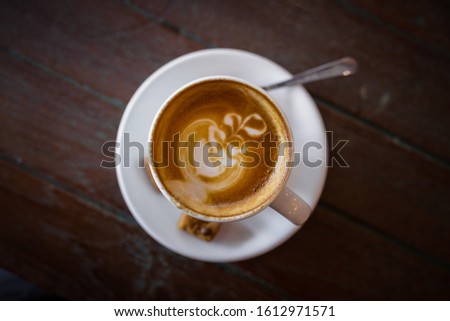 Picture of latte hot coffee with foam milk art on a wooden table