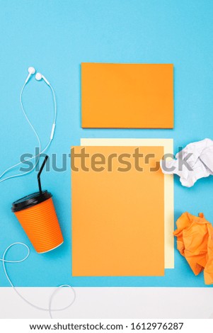 minimalism concept. paper cup and paper sheets with a mockup on a blue background with copy space