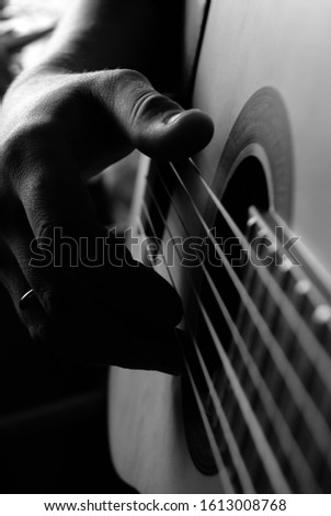 black and white close-up photo of a musical instrument guitar with strings and a male hand. for signage shop labels flyers advertising banners
