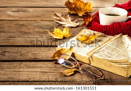 Hot coffee, vintage book, glasses and autumn leaves on wood background - relax or retirement concept with free text space