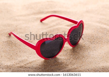 Modern heart shaped sunglasses on the beach sand