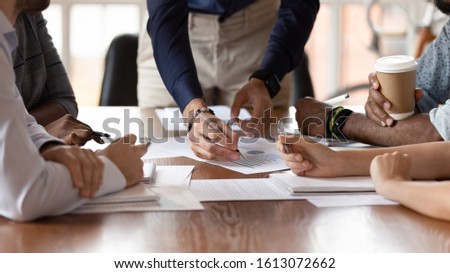 Close up of multiethnic millennial colleagues coworkers sit at office desk discuss business ideas consider paperwork together, diverse businesspeople brainstorm over financial statistics at meeting Royalty-Free Stock Photo #1613072662