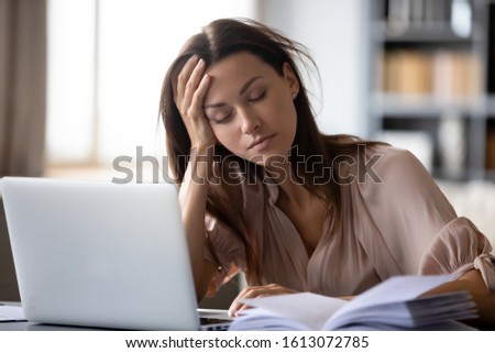 Tired millennial girl student sit at desk fall asleep studying late hours at laptop at home, exhausted young woman take nap sleep at workplace working on computer, exhaustion, fatigue concept Royalty-Free Stock Photo #1613072785