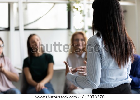 Rear back view female african ethnicity participant at group rehab session telling story share personal problem with associates or corporate staff gathered together listening business coach at seminar Royalty-Free Stock Photo #1613073370