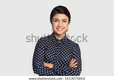 Head shot studio portrait millennial pleasant attractive smiling indian ethnicity confident student, young specialist, intern or employee looking at camera, isolated on grey studio background.
