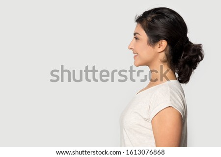 Side profile view smiling happy millennial indian ethnicity girl standing on right, looking at empty copy space for advertising text, product service promotion, education job opportunity announce. Royalty-Free Stock Photo #1613076868
