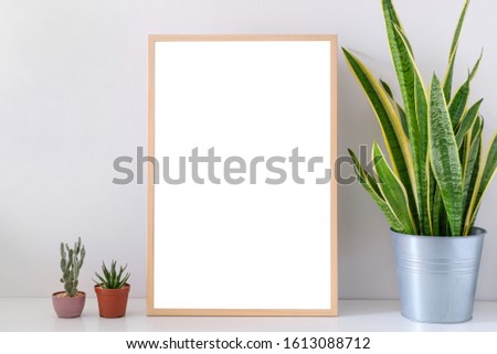 Mock up Photo frame on table with green plants in pot