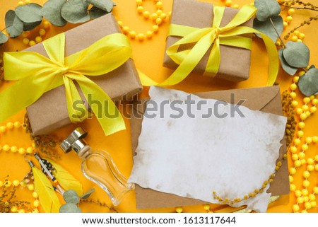 romantic composition in yellow colors. gift box, perfume bottle, jewelry and envelope. place for text. top view