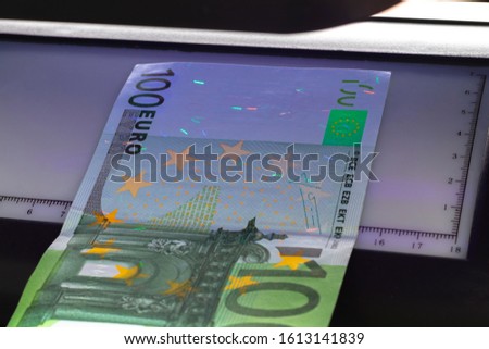 100 Euro banknote. Lying in the ultraviolet to verify the authenticity of banknotes. Close-up.