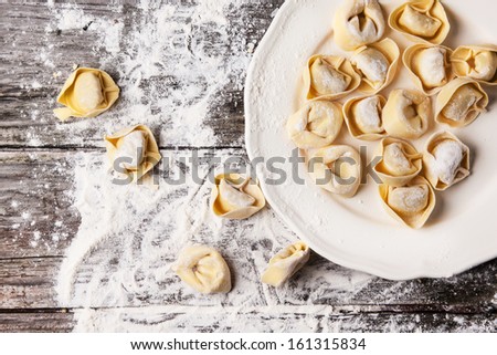 Top view on plate of homemade pasta ravioli over wooden table with flour Royalty-Free Stock Photo #161315834