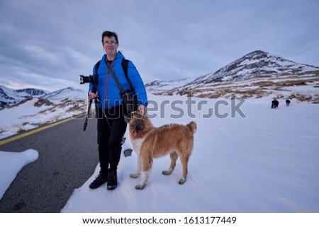 Man and his dog in the mountains in the snow