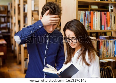 Two annoyed students at the library reading to material for the classes, can't understand it, trying to figure out it`s meaning Royalty-Free Stock Photo #1613190142