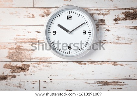minimalist white wall clock with light metal on wooden background texture