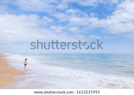 Small boy running be the seashore in the waves