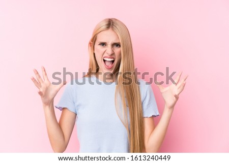 Young blonde woman on pink background screaming with rage.