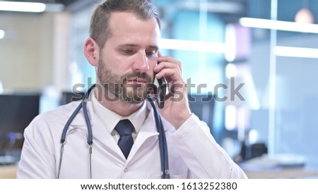 The Portrait of Young Doctor talking on Smartphone in Office