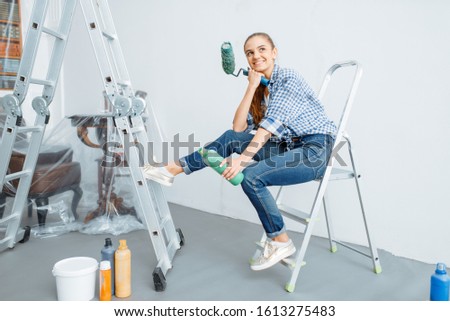 Female house painter sitting on a ladder