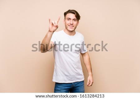 Young caucasian man posing isolated showing a horns gesture as a revolution concept.