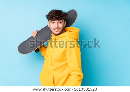 Young arab skater man isolated looks aside smiling, cheerful and pleasant.