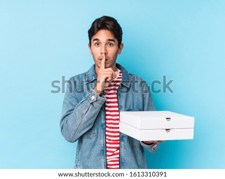 Young caucasian man holding pizzas isolated keeping a secret or asking for silence.