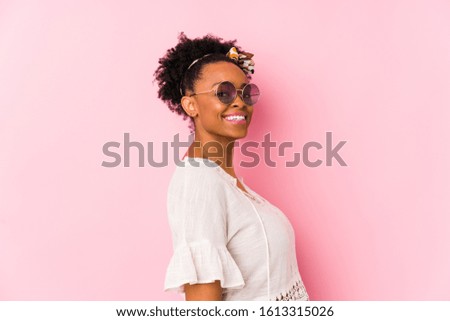 Young african american hipster woman isolated looks aside smiling, cheerful and pleasant.