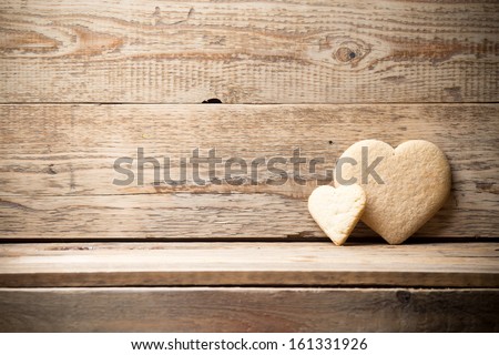 Heart-shaped biscuit on wooden background.
