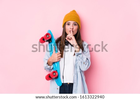 Young skater woman holding a skate keeping a secret or asking for silence.
