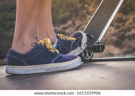 Close up view of teen's feet on a scooter ready to start a ride over the half pipe. Skater starting jumps and tricks at the skate park. Let's go enjoying. Youth, future brave, danger, risk concept