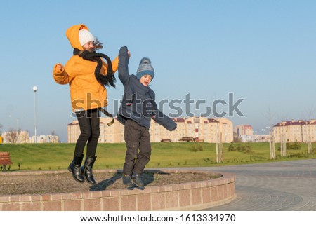 Teenage girl with younger brother walking in the new Park