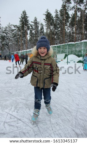 Seven-year-old boy in a warm jacket and hat is ice skating in the winter forest