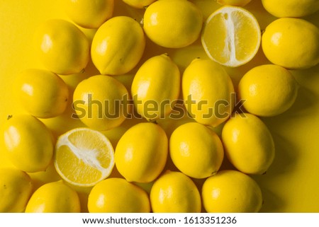Top view many ripe lemons on a yellow surface, background or concept