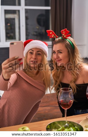 Young girls celebrating New Year taking pictures of themselves while sitting in kitchen.