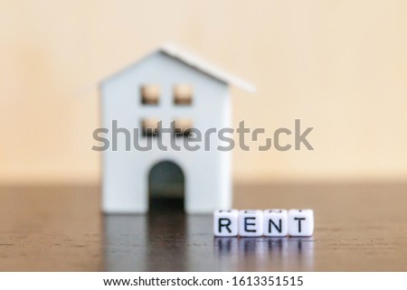 Miniature toy model house with inscription RENT letters word on wooden backdrop. Eco Village abstract environmental background. Real estate mortgage property insurance sweet home ecology rent concept