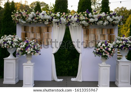 Wedding decor. Wall decorated with books and flowers. Original wedding floral decoration.