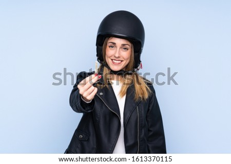 Young blonde woman with a motorcycle helmet and a key over isolated blue background