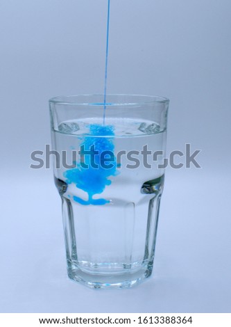 Glass of water with burst of blue color from water enhancer