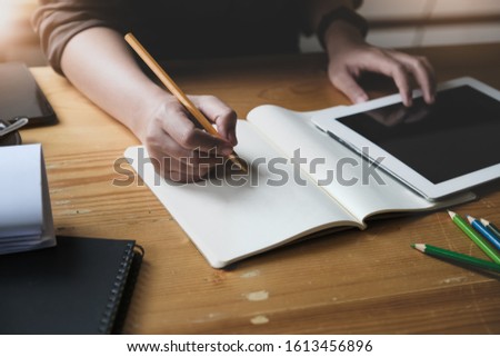 Young woman working with color pencil and notebook and tablet for using design or creative  to drawing Draw clothes design. freelance at work concept.