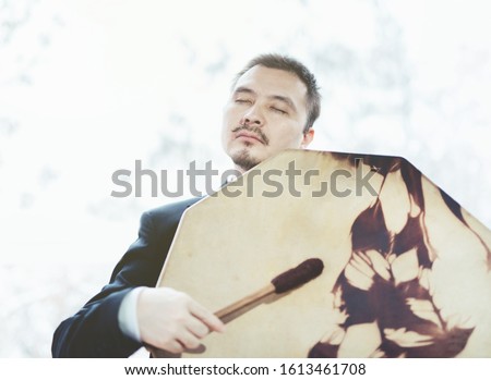 Asian businessman with shamanic tambourine. Concept of attracting success, wishing good luck to business.  Money increasing. 