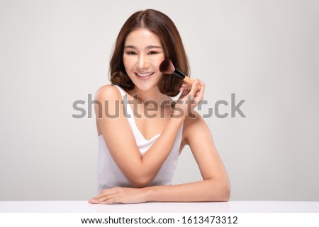 Beautiful Asian young woman smile and holding make up brush with healthy Clean and Fresh skin feeling so happiness and cheerful,Isolated on white background,Beauty Cosmetics Concept