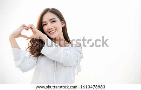 Portrait of young beautiful asian woman hands gesture in heart shape on city sky roof top. Smile face asian girl wear casual cloth. Japanese girl lifestyle, lovely woman valentinesâ€™ day concept 