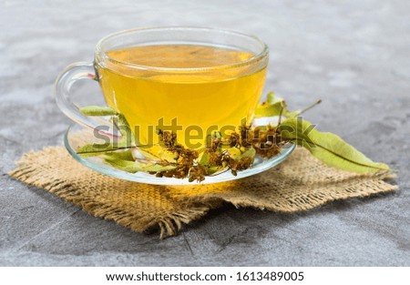 Glass cup of tea from linden flowers on a gray background. The concept of healthy teas.