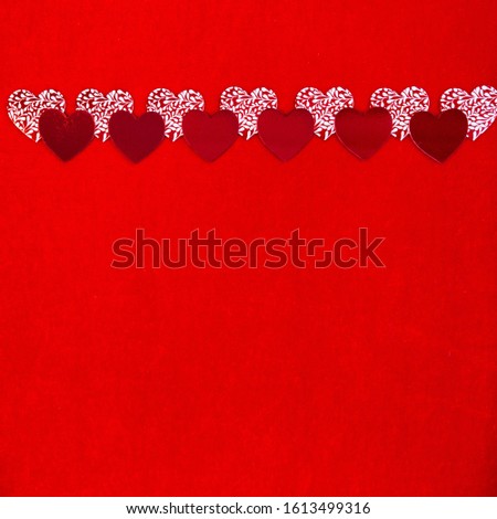 Background for Valentine's day. On top of the banner, red and white Valentine hearts are placed horizontally on a bright red velvet background. Square background, lots of space for text