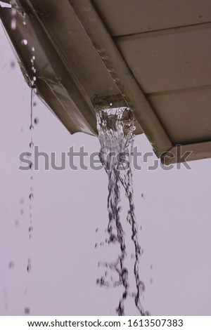 A missing downspout from a gutter system, showing gallons of rain flooding. Royalty-Free Stock Photo #1613507383
